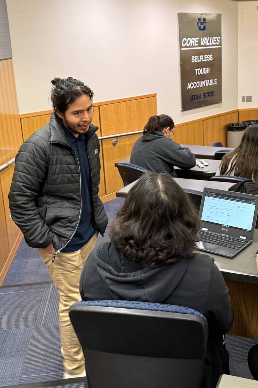 advisor speaking with student in a classroom